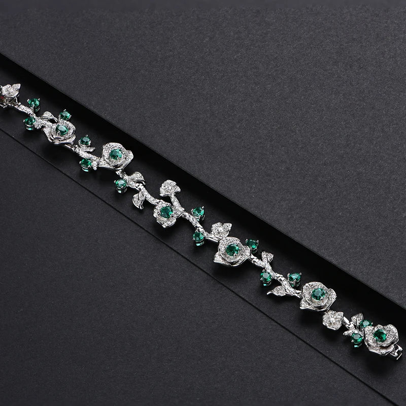 Silver bracelet with green stones and leafy vine design