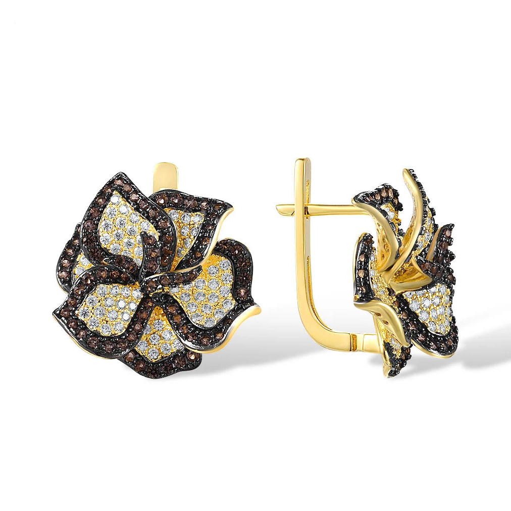 Gold earrings shaped like trillium flowers, paved with white and brown gemstones.