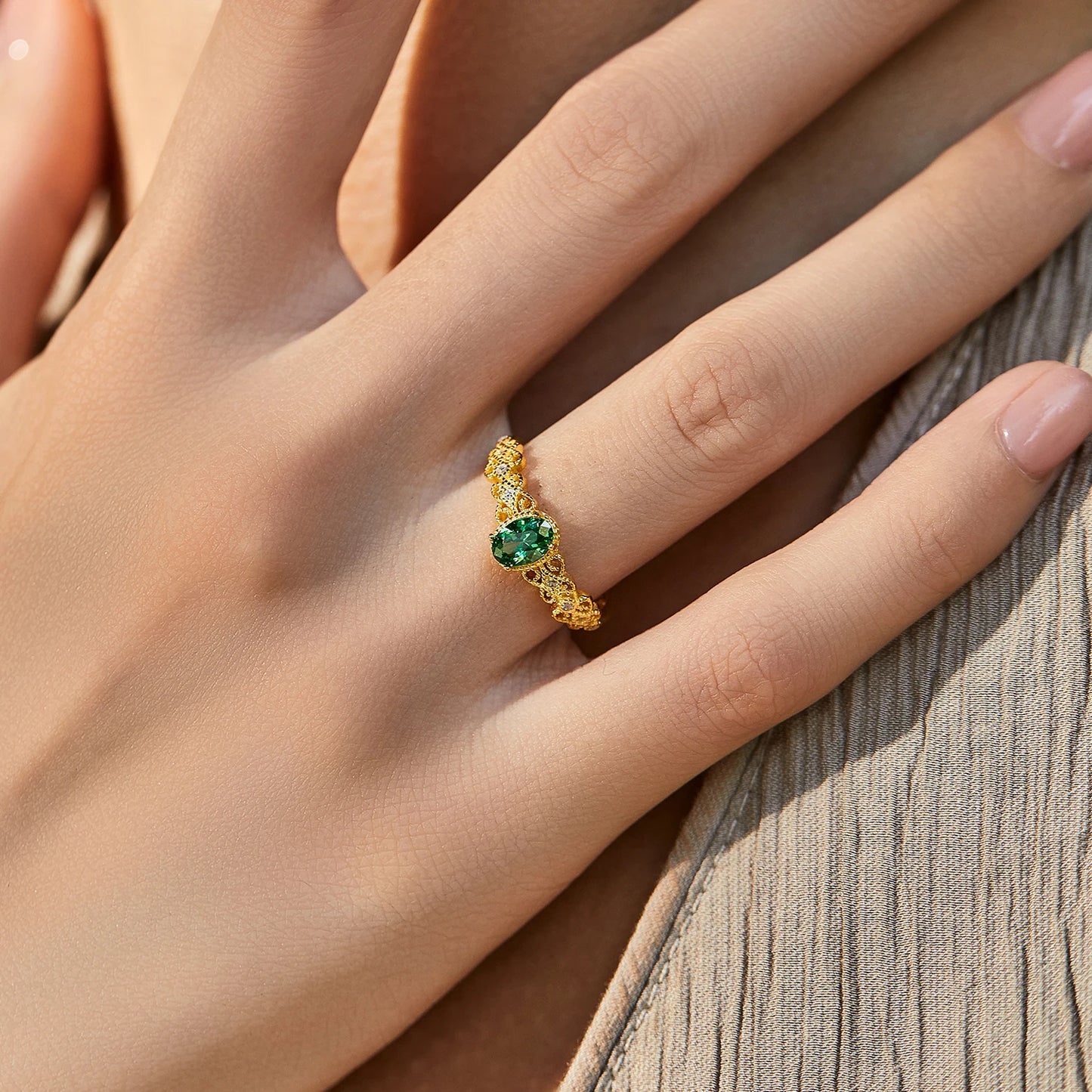 Gold-plated silver ring with a green oval gemstone and delicate diamond-accented detailing.