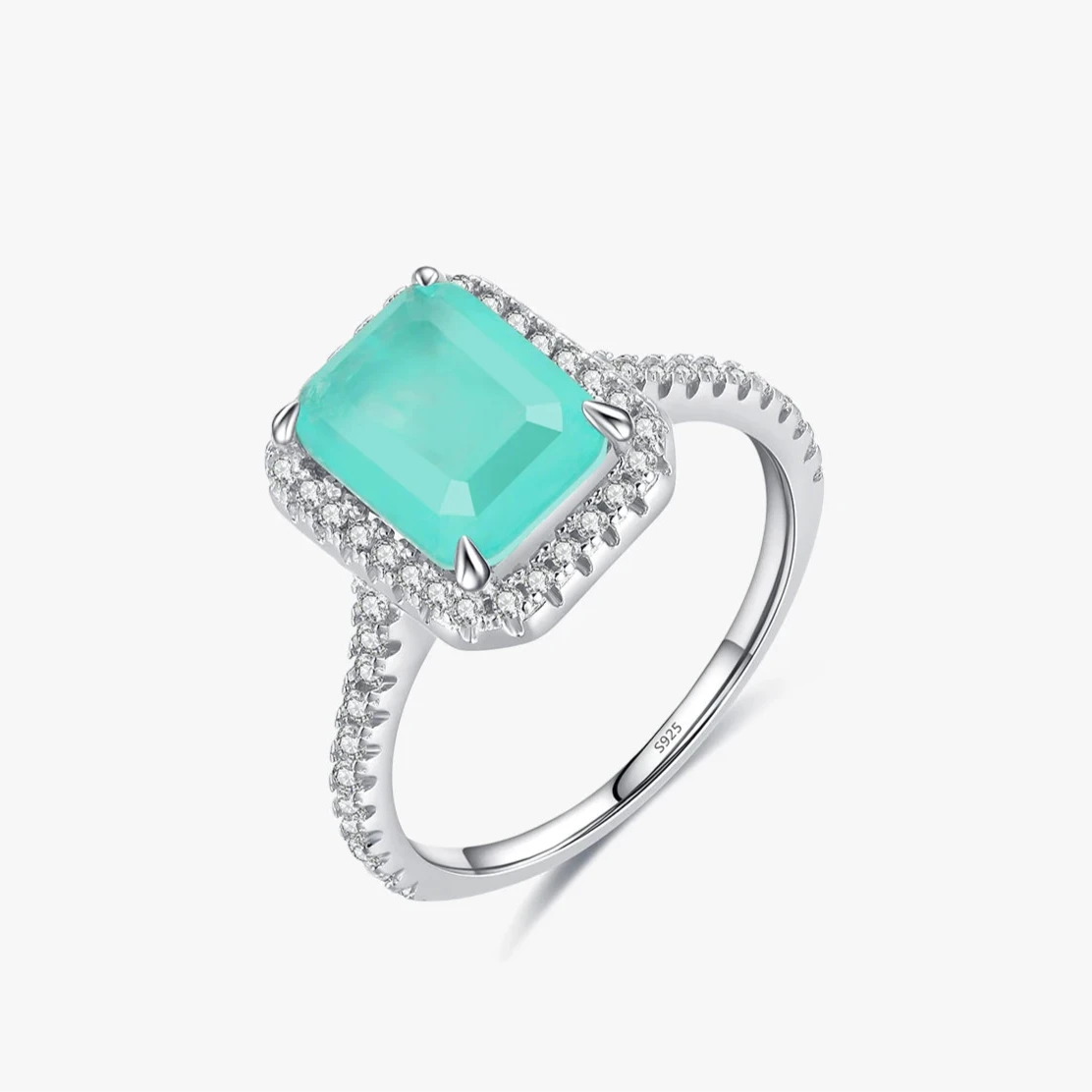 Rectangular green gemstone ring with a halo of clear stones on a silver band.