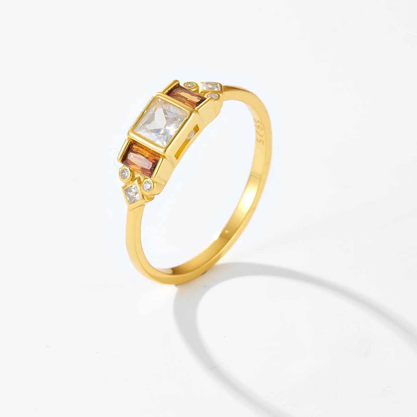 Gold ring with central white stone flanked by smoky square-cut stones and small accent gems