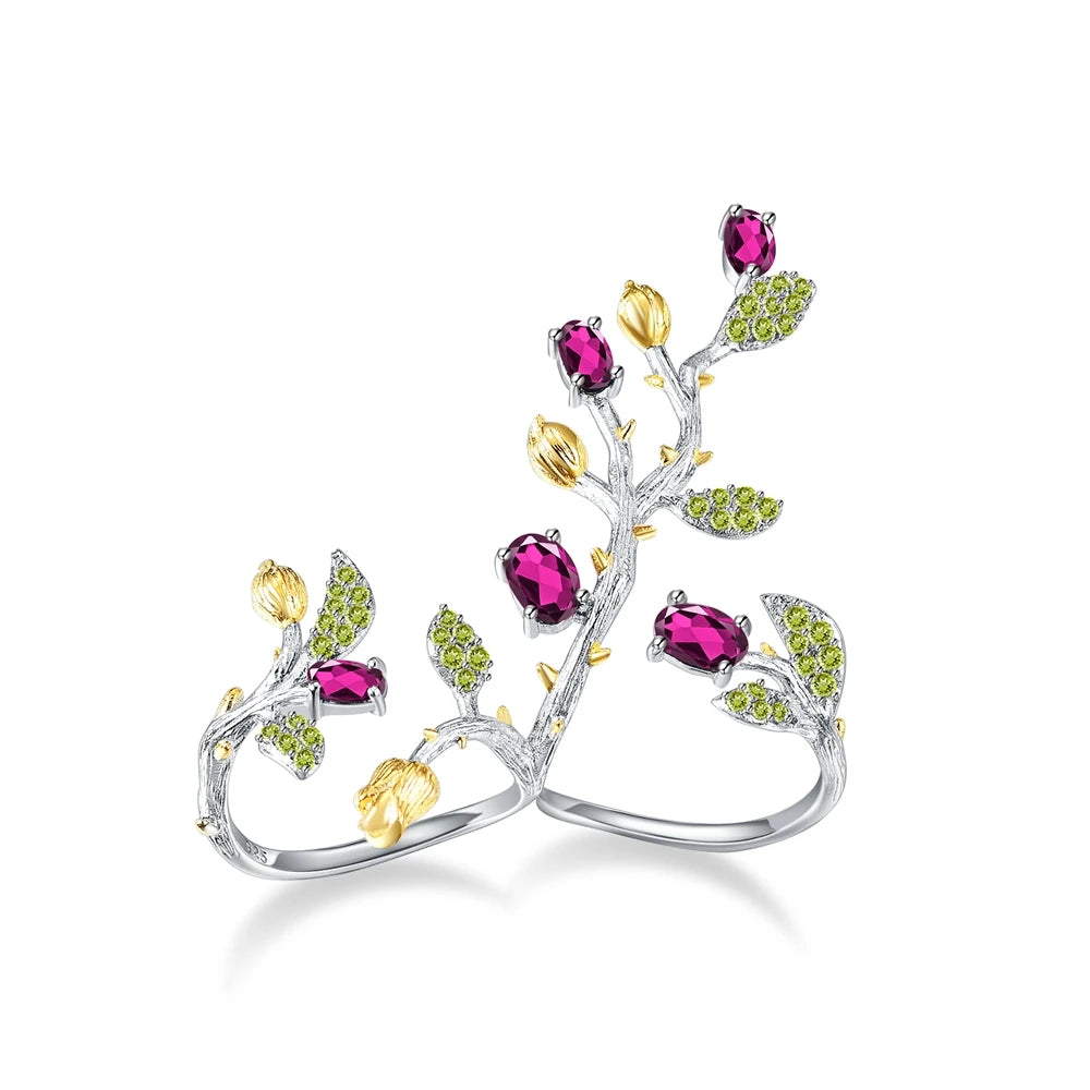 Double-finger ring with branch-like silver bands, deep pink stones, golden buds, and green pavé leaves from the Rossa Collection.
