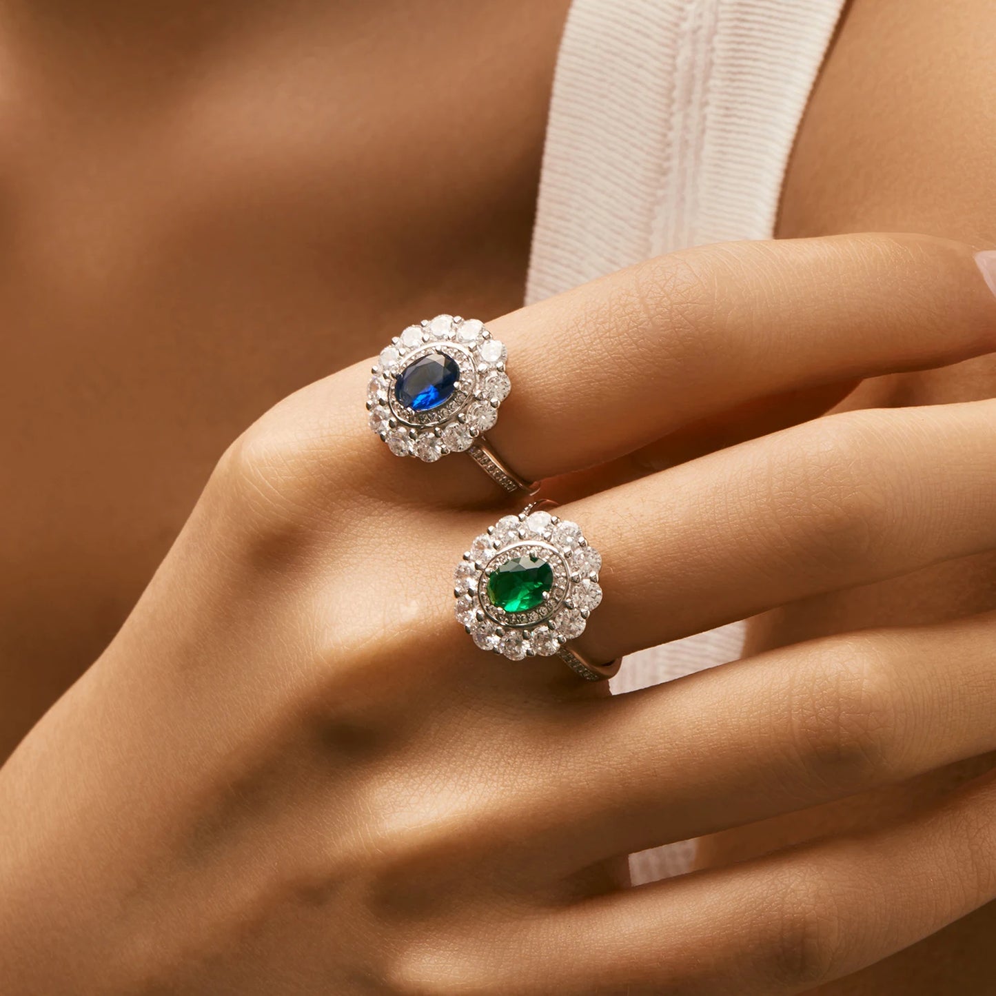 Silver ring with an oval deep blue or green stone surrounded by two halos of clear zirconia stones