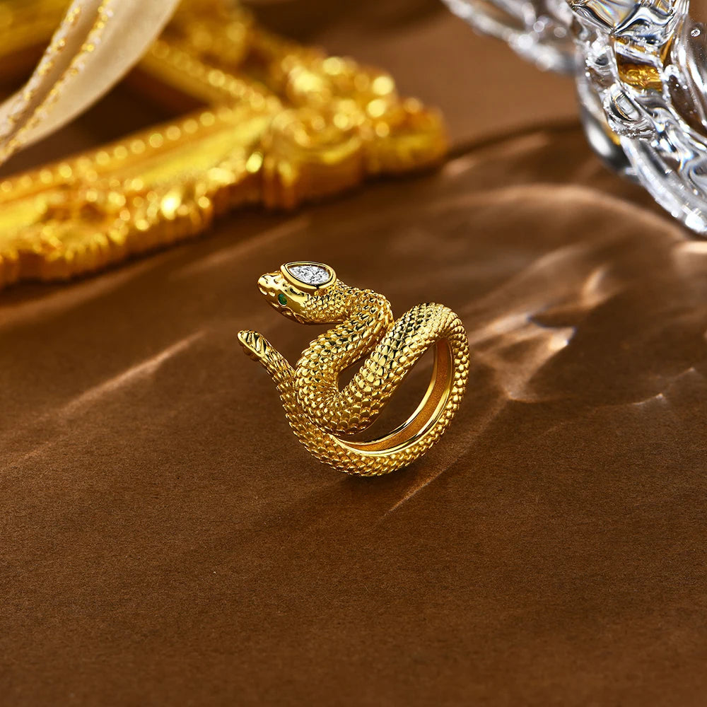Textured silver snake ring coiled in a striking pose with green eyes and a marquise-cut clear stone set in the head.