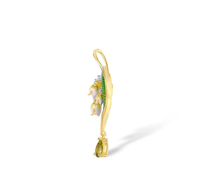 Close-up of a nature-inspired jewelry set featuring a green enameled leaf design with white and yellow floral elements, accented with sparkling stones and gold detailing.
