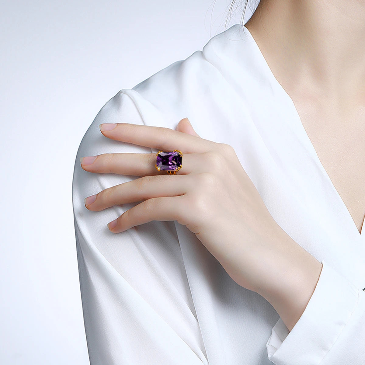 Gold rings with large square-cut gemstones in amethyst purple, deep sapphire blue, icy aquamarine, and bright sky blue on a light blue background