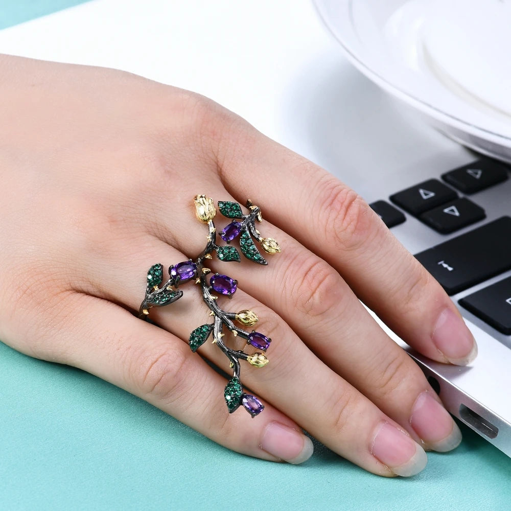 Double-finger black ring shaped like a flowering branch with purple, green, and gold detailing