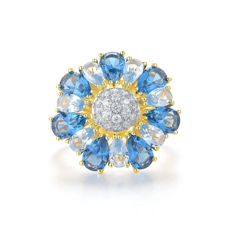 Gold ring shaped like a flower with alternating blue and clear pear-shaped stones around a pavé-set centre