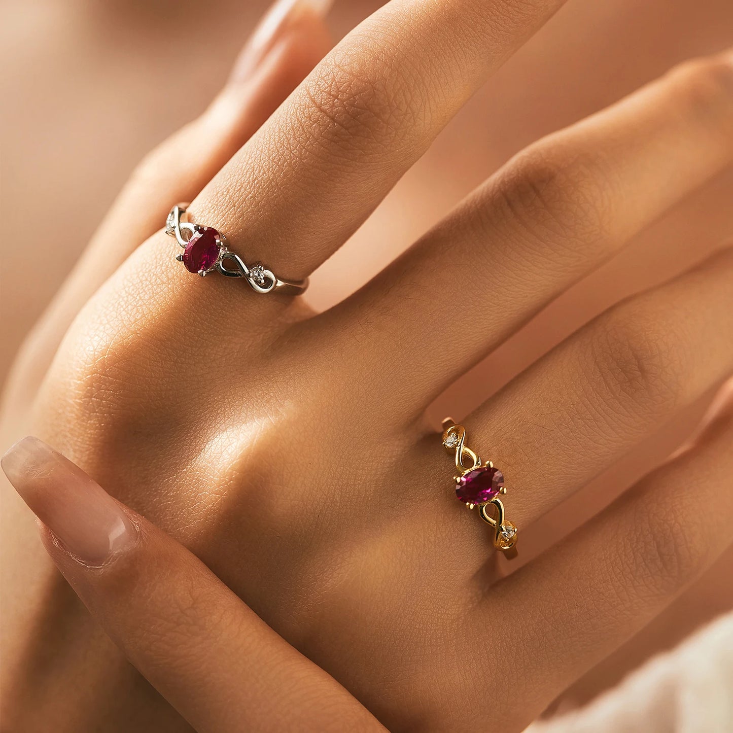 Gold-plated ring with an oval pink gemstone and twisted infinity-style band