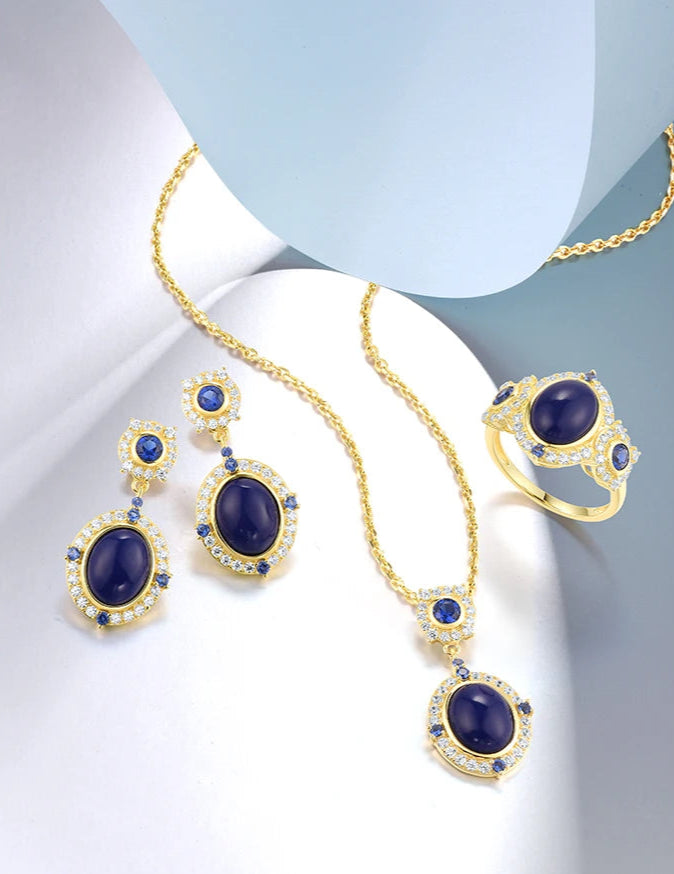Gold jewelry set featuring oval deep blue stones with clear and sapphire-toned halo accents