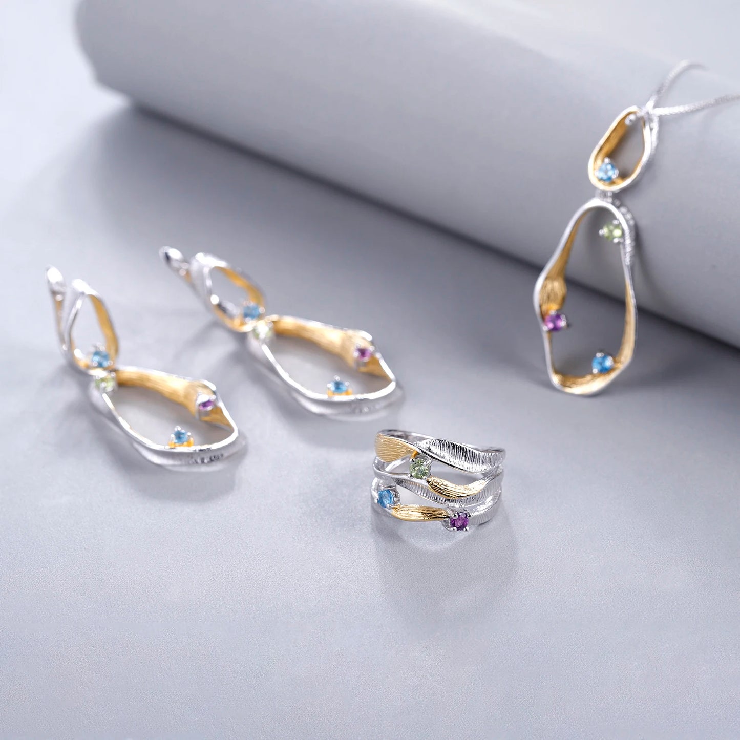 Jewelry set with flowing gold and silver design featuring sky blue gemstones – necklace, earrings, and ring