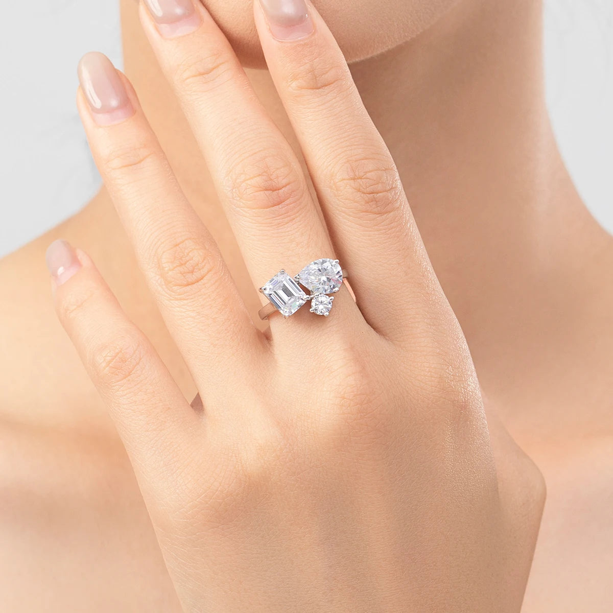 Silver ring with a mix of emerald, pear, and round-cut clear stones in an asymmetrical setting