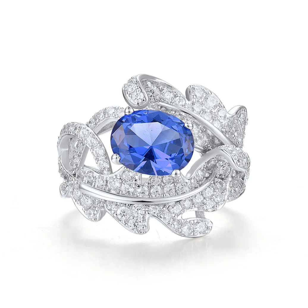 Silver ring with fern-like design, white pavé stones, and deep blue oval gemstone
