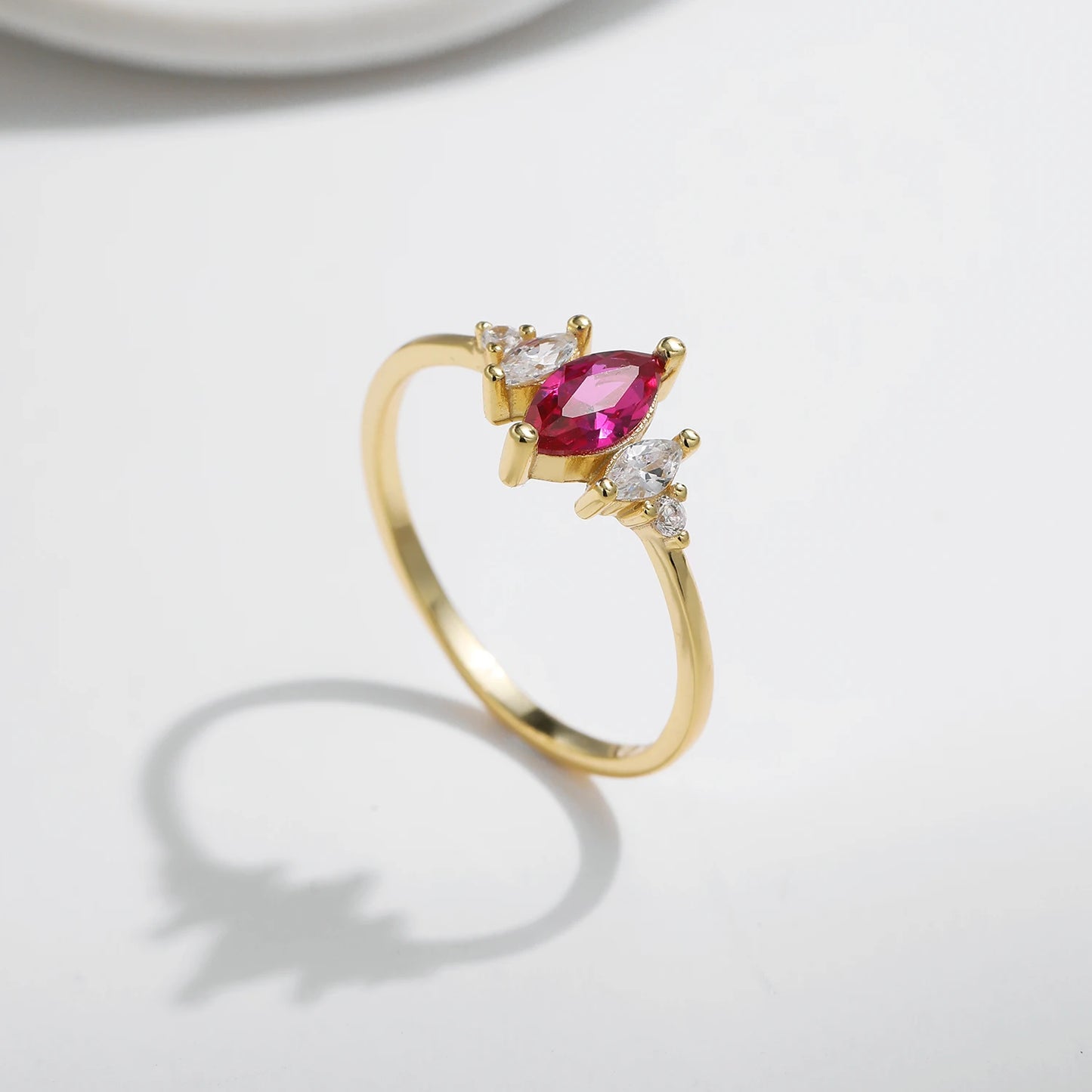 Gold-plated ring with marquise-cut ruby-pink stone and clear side accents