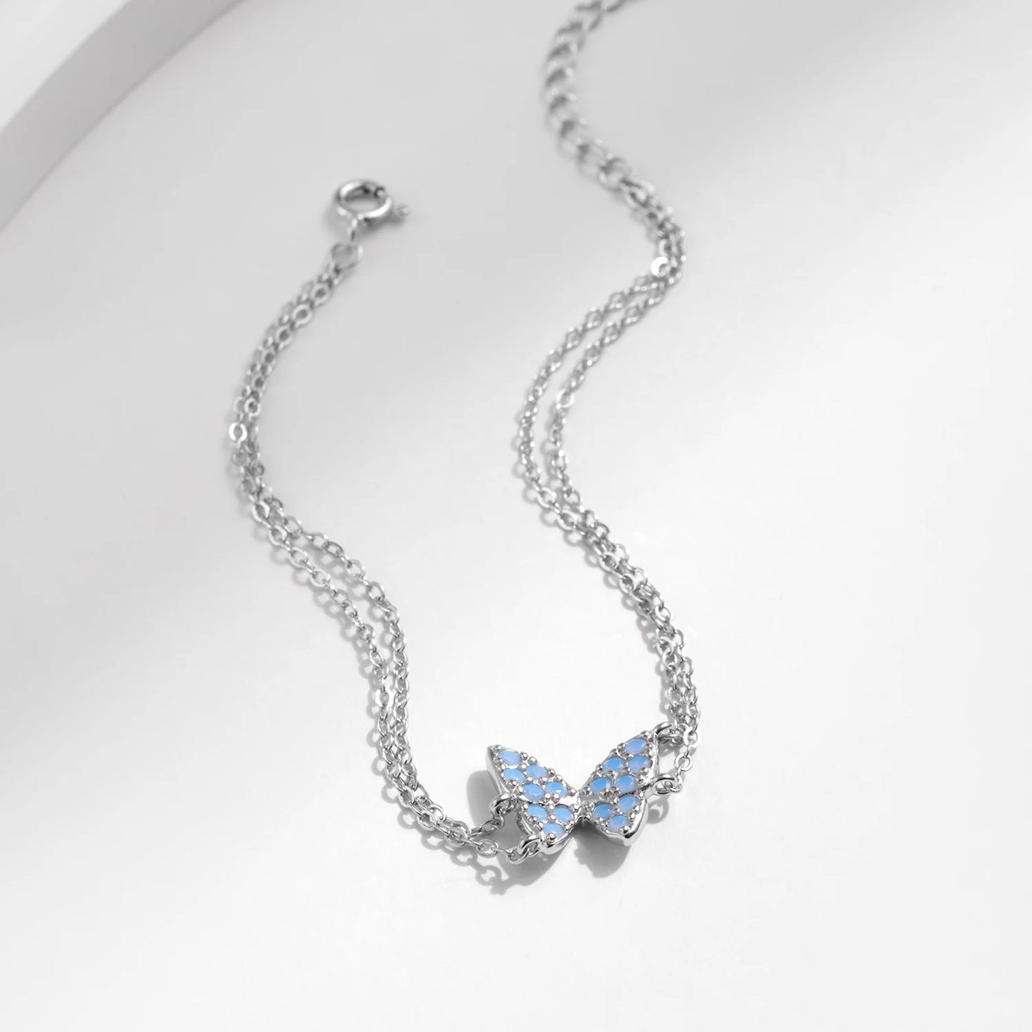 Delicate silver bracelet with a central opal butterfly charm and fine double chain