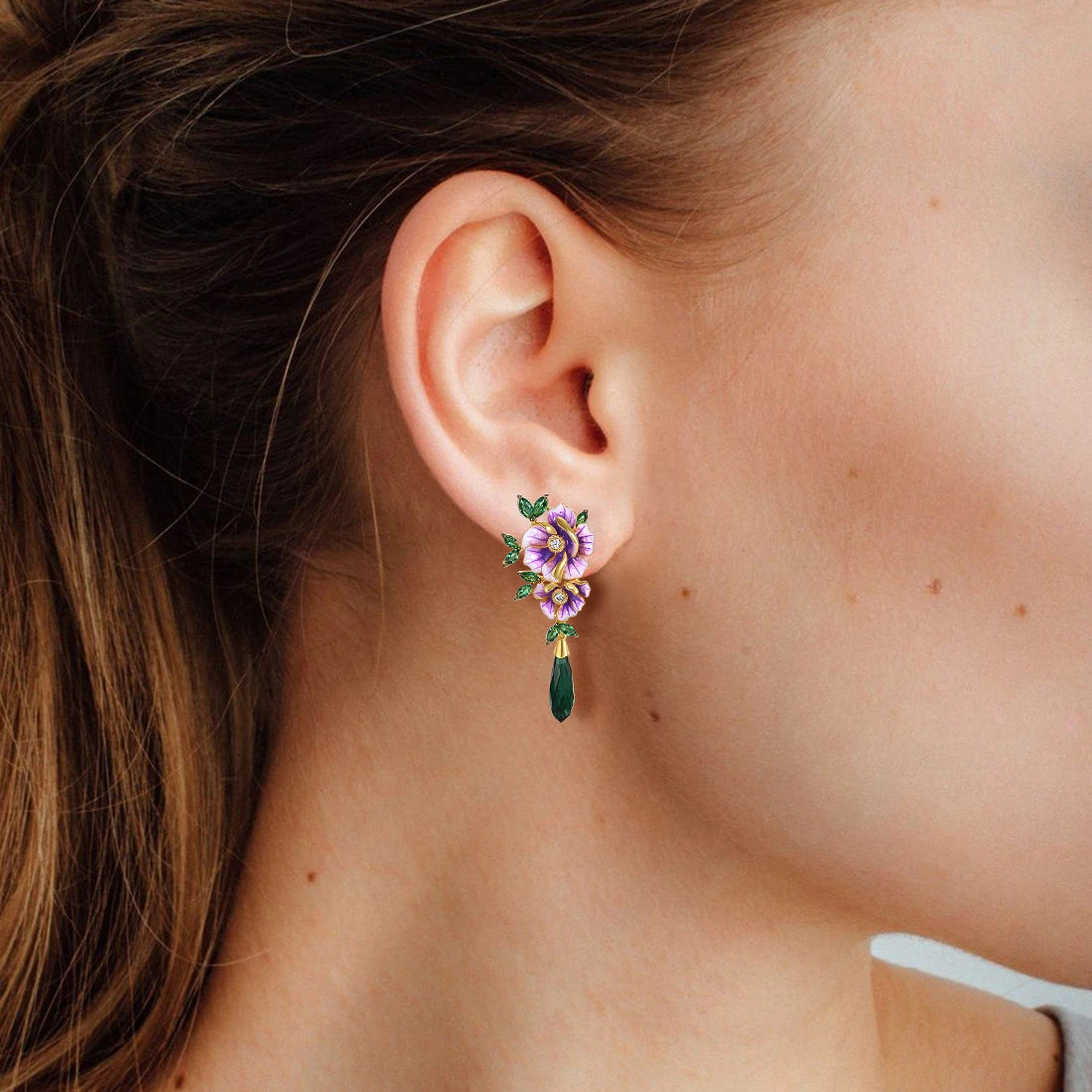 Gold earrings with purple enamel flowers, green marquise leaves, and elongated dark green crystal drops