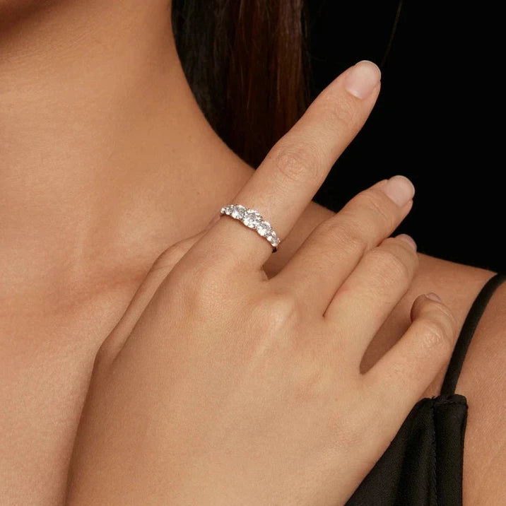 Silver band ring adorned with a sequence of round brilliant-cut stones, creating a continuous sparkling design.