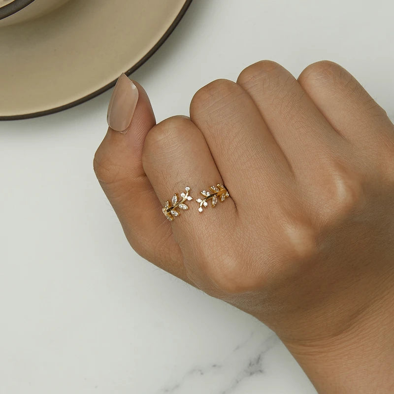 Gold-plated ring featuring two leafy branches set with clear stones, delicately curving toward each other in an open design, from the Bianco Nero collection.