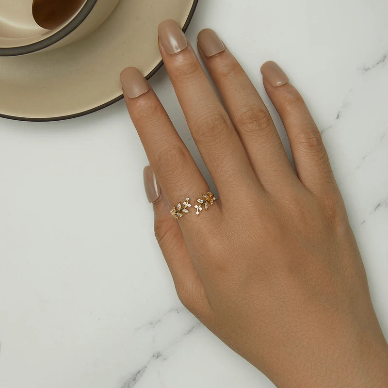 Gold-plated ring featuring two leafy branches set with clear stones, delicately curving toward each other in an open design, from the Bianco Nero collection.