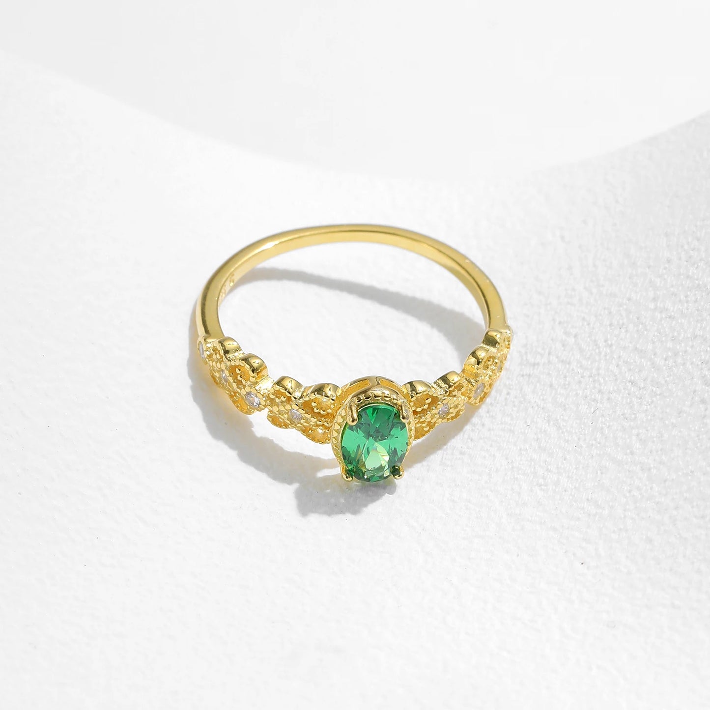 Gold-plated silver ring with a green oval gemstone and delicate diamond-accented detailing.