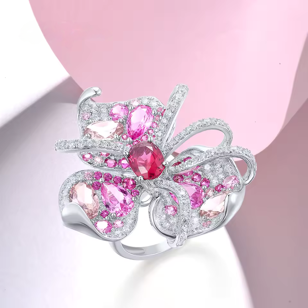 Lalicata ring shaped like an abstract floral design, adorned with pink and red gemstones set in polished silver.
