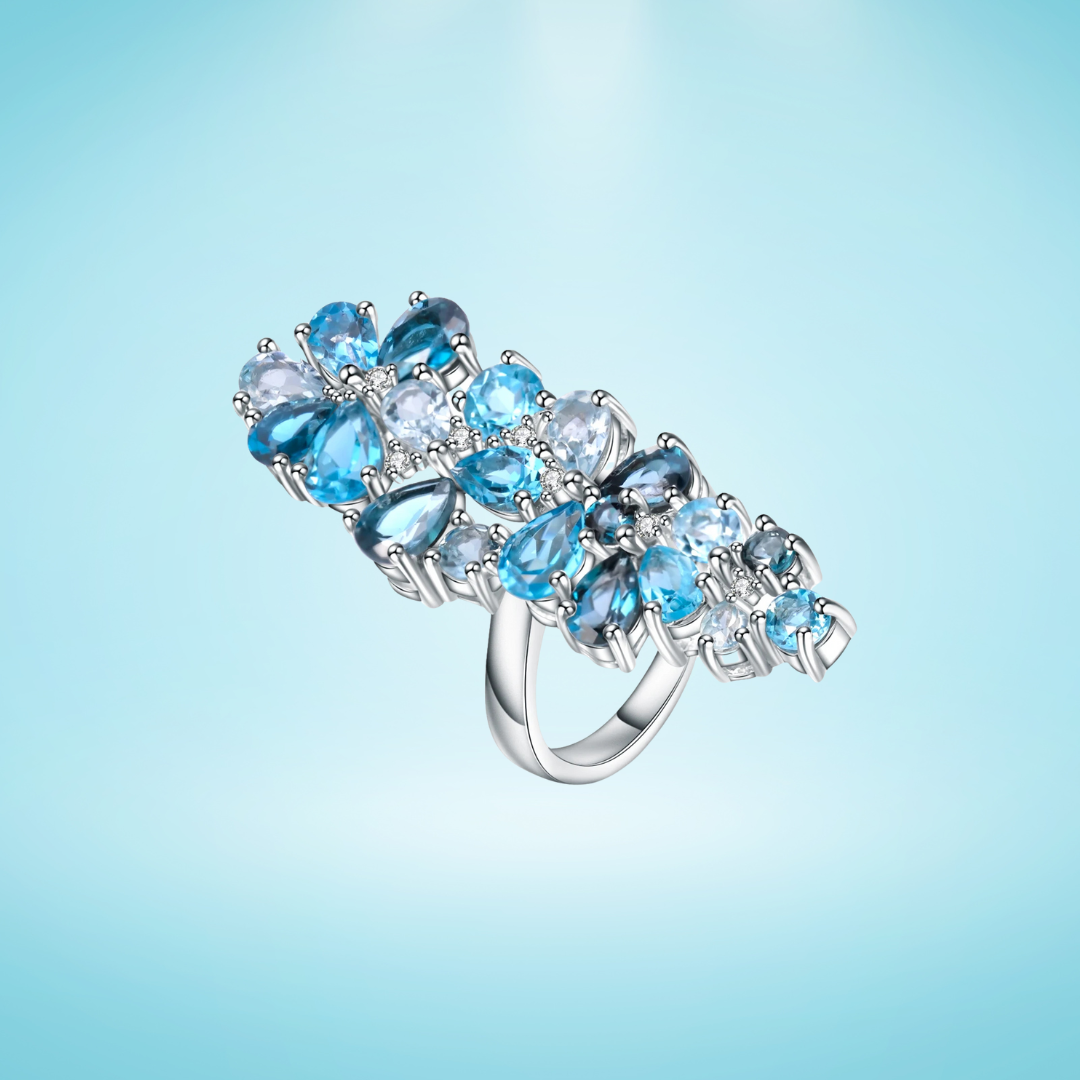 Sterling silver ring adorned with clusters of pear-cut and round-cut blue topaz gemstones in varying shades.