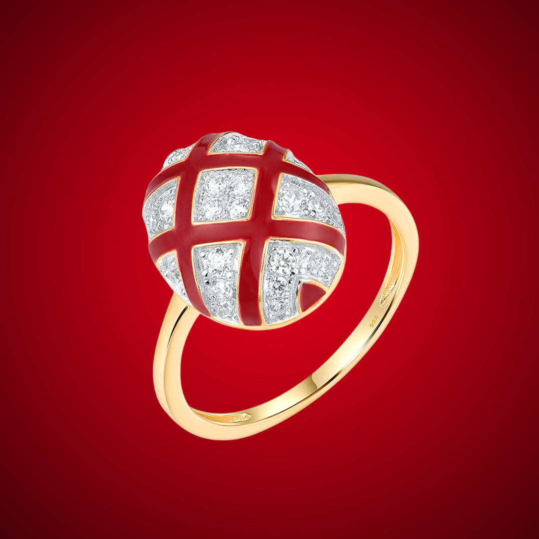 Gold ring with a domed top featuring a red enamel criss-cross design over pavé white stones.