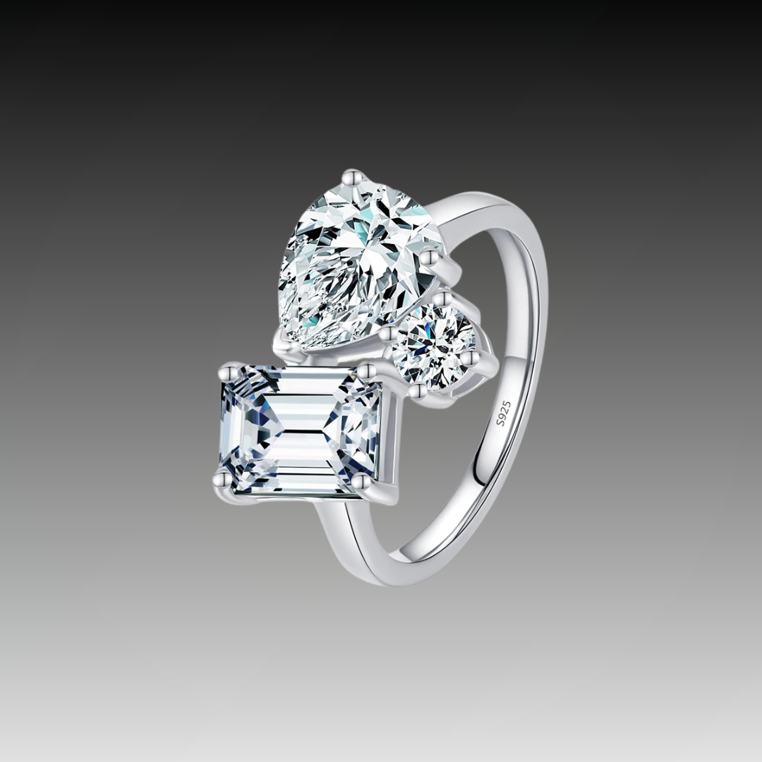 Silver ring with a mix of emerald, pear, and round-cut clear stones in an asymmetrical setting
