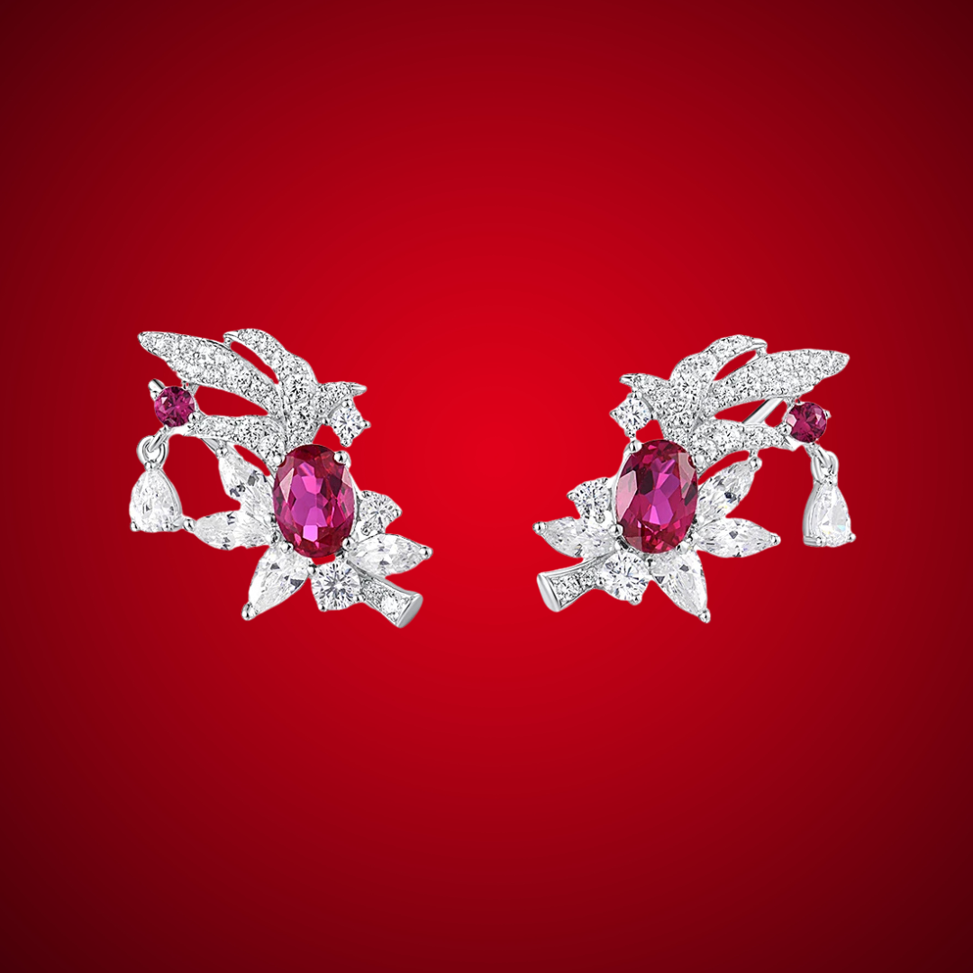 Birmania earrings featuring vivid oval ruby-colored stones surrounded by white crystal floral accents and pear-cut dangles.