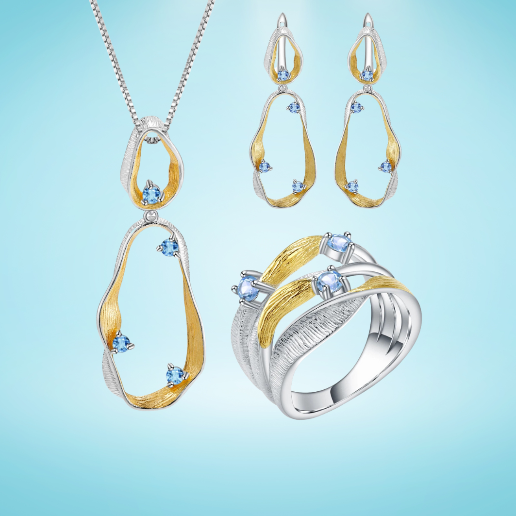 Jewelry set with flowing gold and silver design featuring sky blue gemstones – necklace, earrings, and ring