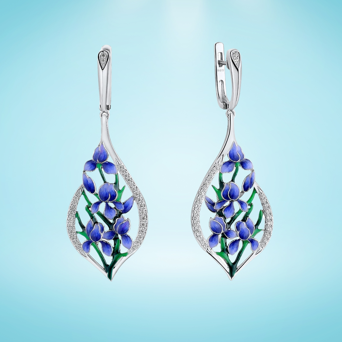 Sterling silver drop earrings featuring blue and green enamel floral vines framed in teardrop-shaped pavé-set silver, on a light blue background