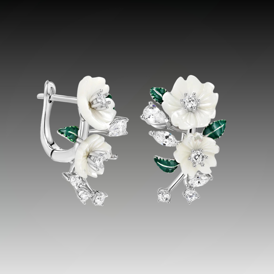 Silver earrings with carved white flowers, green enamel leaves, and clear gemstones