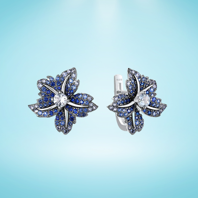Silver earrings shaped like lilies, encrusted with deep blue and white stones

