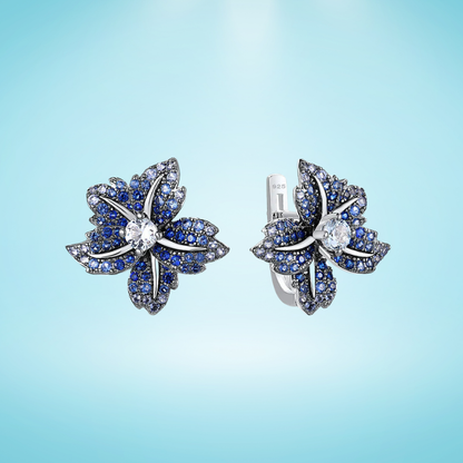 Silver earrings shaped like lilies, encrusted with deep blue and white stones

