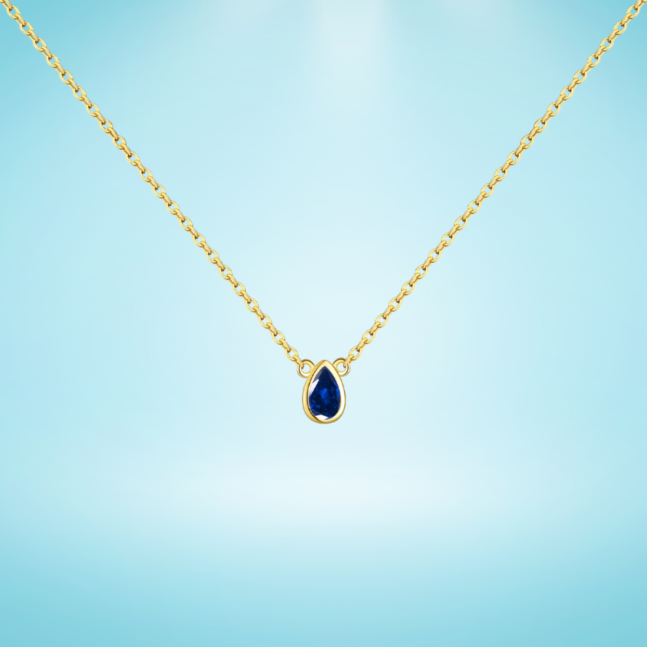 Gold chain necklace featuring a pear-shaped deep blue gemstone in a bezel setting