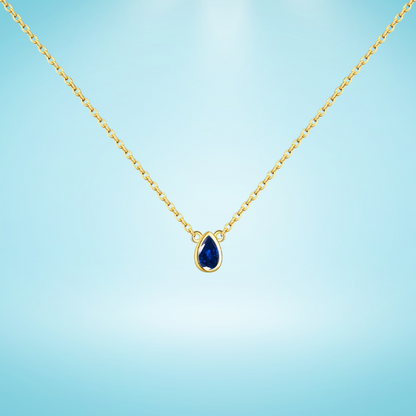 Gold chain necklace featuring a pear-shaped deep blue gemstone in a bezel setting