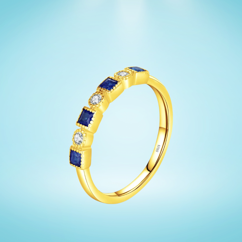 Gold ring with alternating square blue stones and round clear stones

