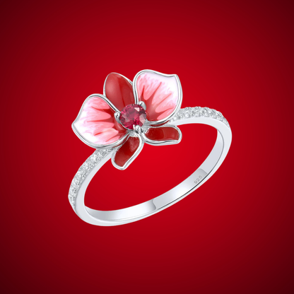 Silver floral ring featuring a red and white enamel orchid with a central ruby-colored stone.

