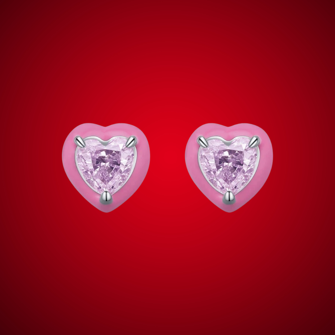 Stud earrings shaped like soft pink hearts, each set with a sparkling light pink heart-cut gemstone.

