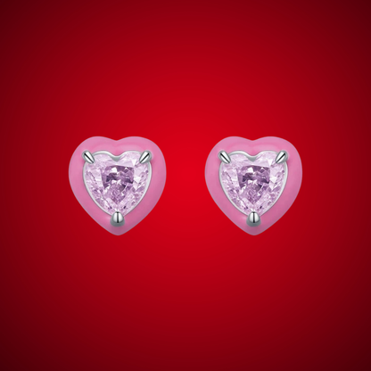 Stud earrings shaped like soft pink hearts, each set with a sparkling light pink heart-cut gemstone.

