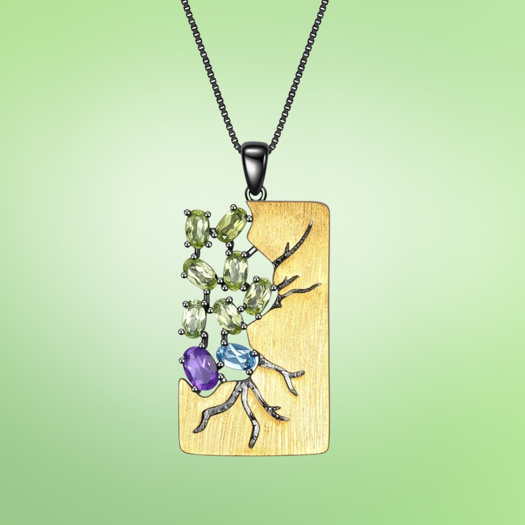 Gold pendant necklace featuring a gemstone tree design with green, blue, and purple stones

