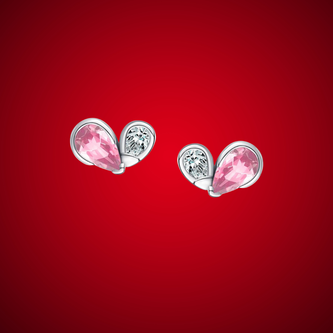 Pair of silver earrings featuring a pink heart-shaped gemstone paired with a smaller round clear stone in a modern open setting.


