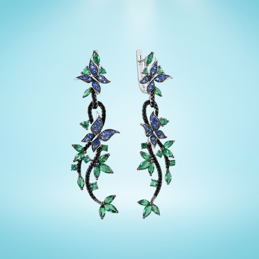 Long silver earrings with blue and green crystal butterflies and vine-like detailing

