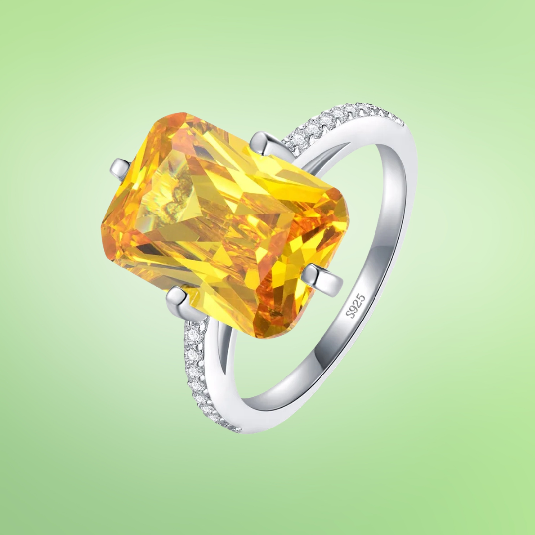 Silver ring with large rectangular yellow gemstone and pavé band detail

