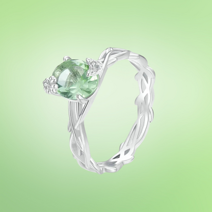 Silver ring with green round gemstone and vine-inspired band design

