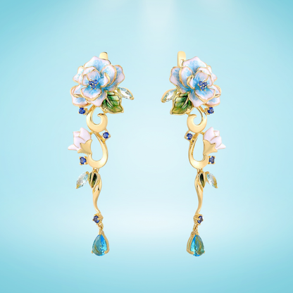 Gold floral earrings with hand-painted white and blue enamel petals, sapphire accents, and dangling blue teardrop stones


