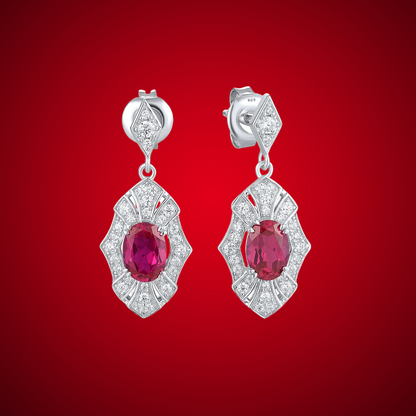 Rubino earrings with deep red oval stones framed in intricate silver settings accented by small white crystals.

