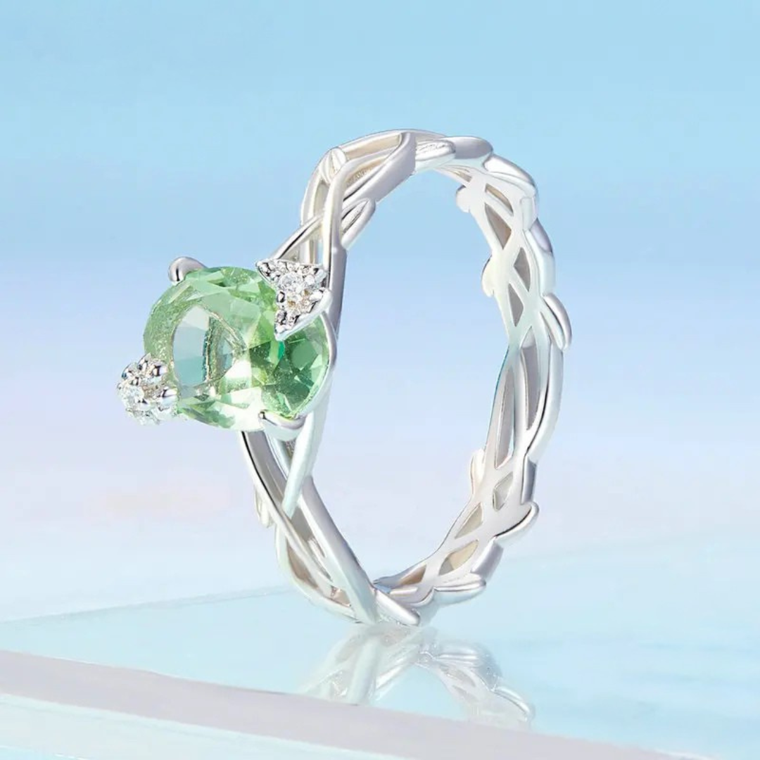 Silver ring with green round gemstone and vine-inspired band design


