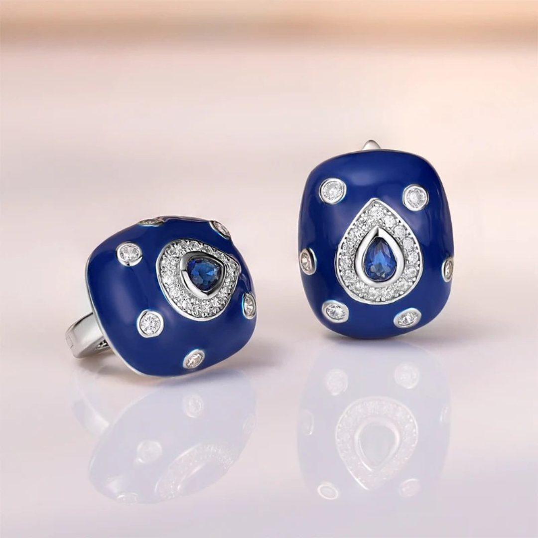 Bold blue enamel earrings with central teardrop-shaped sapphire stones framed by white zircon pavé on a silver base.

