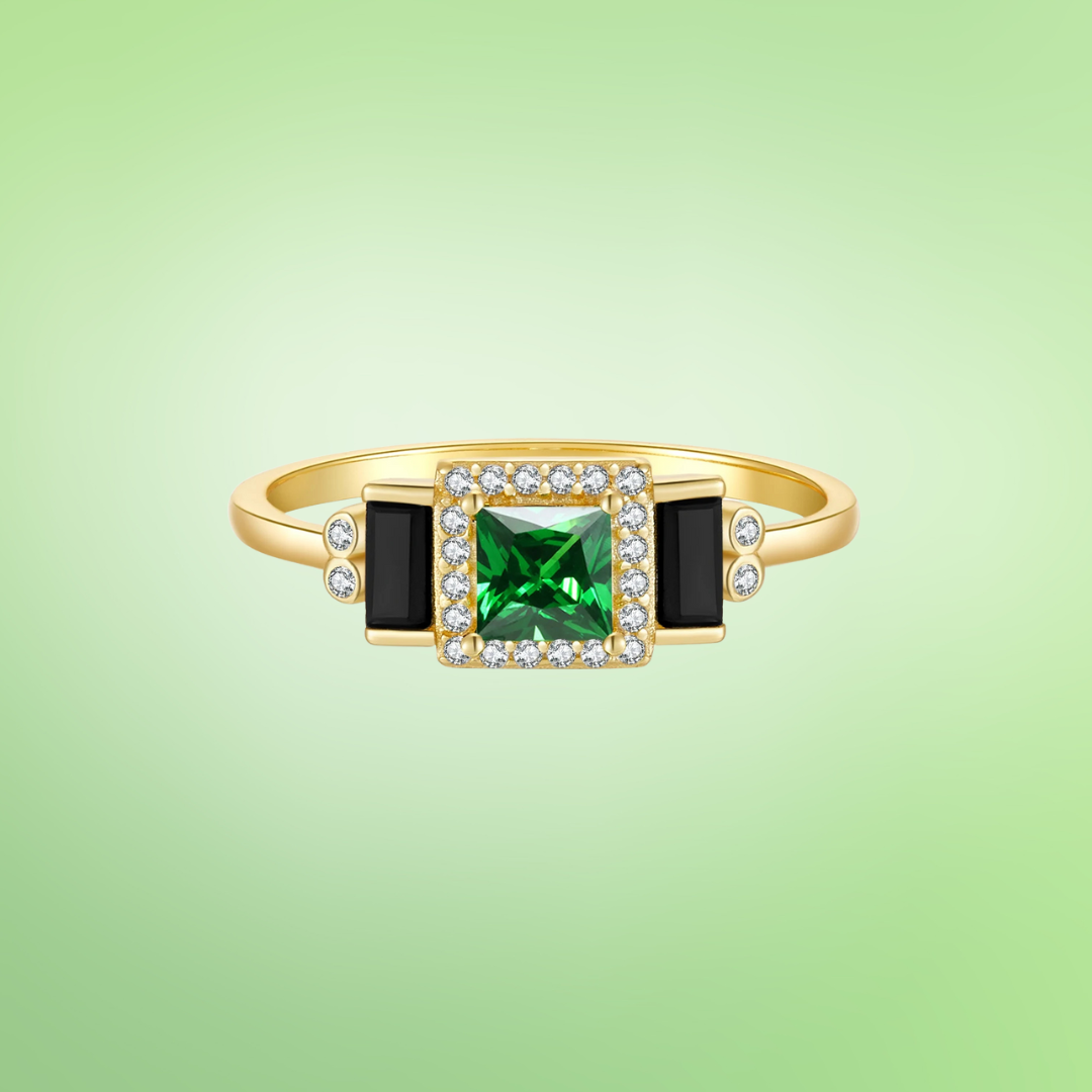 Gold ring with square green center stone, black accents, and pavé border

